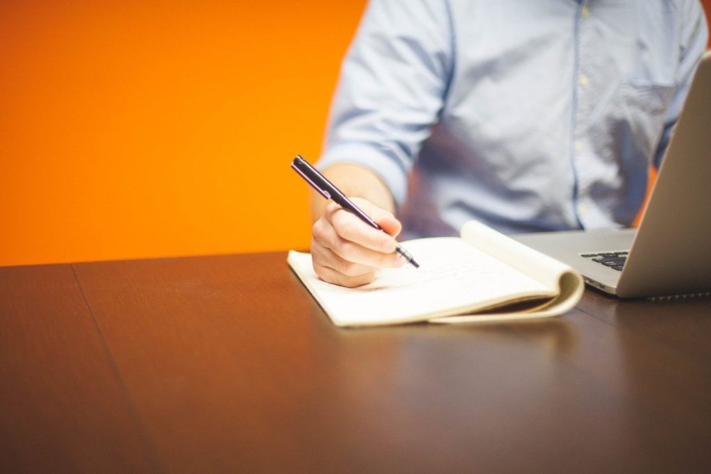 A man is writing on his note book