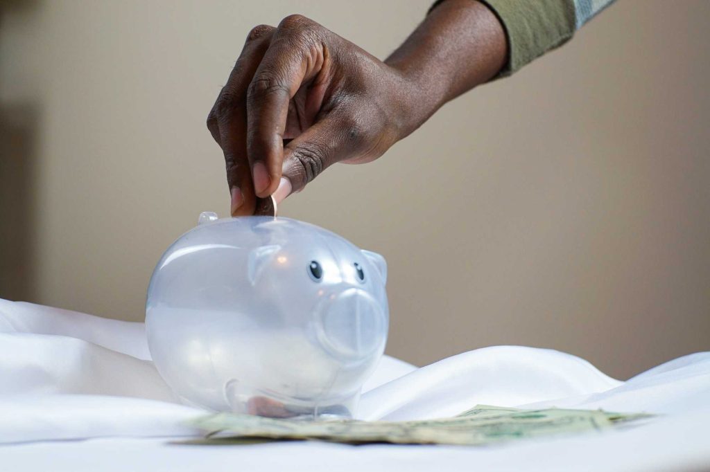 Person putting coin in piggy bank